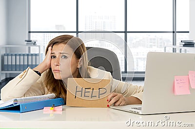 Attractive sad and desperate business woman suffering stress at office laptop computer desk holding help sign Stock Photo