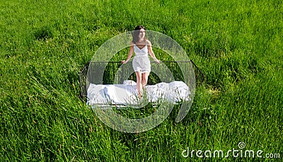 Attractive, satisfied pleased young, sexy, cute, brunette woman outdoors in bed, in white nightwear, on the meadow in the high Stock Photo