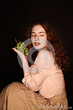 Attractive seductive redhead woman holding fresh green grapes, Stock Photo