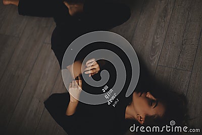 Attractive woman lies on the floor. She looks sensuality. Hot girl wears total black look. Stock Photo