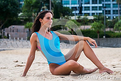 Attractive slender swimwear model posing on sand with resort hotel in the background Stock Photo