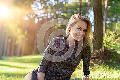 Attractive smiling young blond woman in sportswear, relaxing after workout Stock Photo