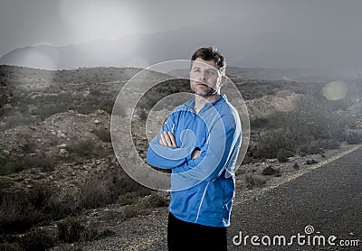 Attractive sport man with folded arms posing cool and defiant attitude in dramatic advertising light style outdoors Stock Photo