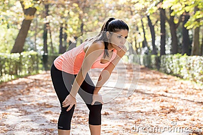 Attractive sport woman in runner sportswear breathing gasping and taking a break tired and exhausted after running workout on Autu Stock Photo