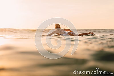 Attractive surfer woman on a surfboard in ocean. Surfgirl at sunset Stock Photo