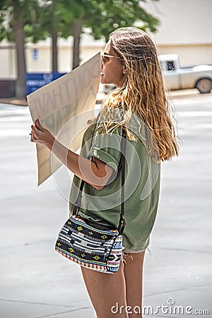 Attractive tanned woman in short shorts and sunglasses with long brunette hair and cute purse stands by Editorial Stock Photo