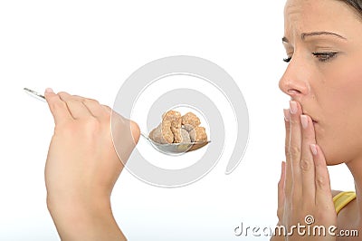 Attractive Unhappy Cautious Young Woman Holding a Spoonful of Brown Sugar Cubes Stock Photo