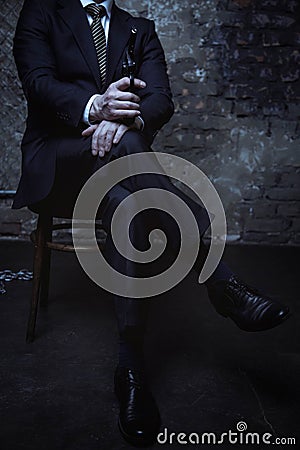 Attractive villain sitting with his legs crossed Stock Photo