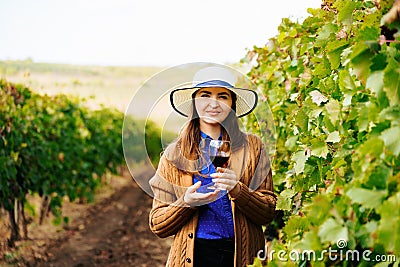 Attractive winemaker woman holding a glass of red wine in her hand and looking at the camera Stock Photo