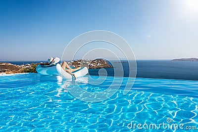 Woman floats on a infinity swimming pool with view to the Mediterranean sea in Greece Stock Photo