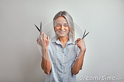 Attractive woman blonde hairdresser with professional tool posing on camera, gray background. Copy space, advertising Stock Photo