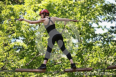 Attractive woman climbing in adventure rope park in safety equipment Stock Photo