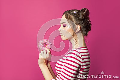 Attractive woman holding donut on vivid pink background, diet concept Stock Photo