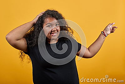 Attractive woman keeping hnd on head, pointing finges aside, looking at camera Stock Photo