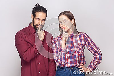 Attractive woman and man standing showing shh gesture keeps secret posing with with finger near lips Stock Photo