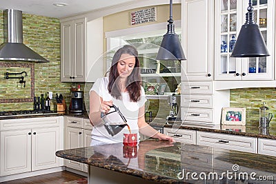 Attractive woman pouring homemade coffee for two in modern sunny kitchen Stock Photo