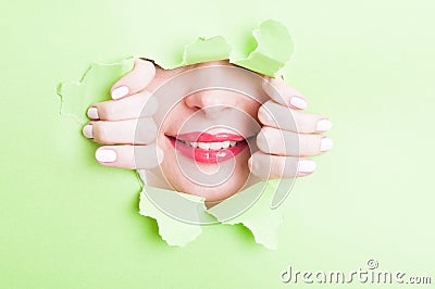 Attractive woman showing beautiful smile thru torn green cardboard Stock Photo