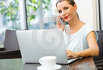 Attractive woman sitting in a cafe with a laptop and talking on Stock Photo