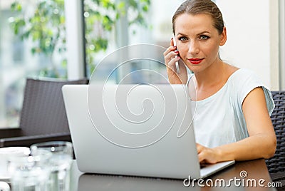 Attractive woman sitting in a cafe with a laptop and talking on Stock Photo