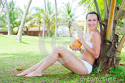 Attractive woman sitting near the palm Stock Photo