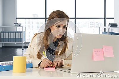 Attractive woman sitting at office chair working at laptop computer desk Stock Photo