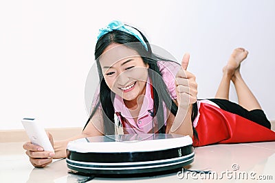 Attractive woman use of remote to control Smart clean robotic vacuum Stock Photo