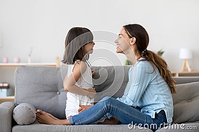 Mother spend time with little daughter talking sitting on couch Stock Photo