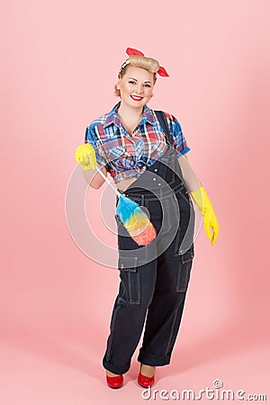 Attractive worker girl with soft colored duster happy to clean. Pin-up girl save hands in gloves Stock Photo