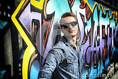 Attractive young blond man against colorful graffiti wall Editorial Stock Photo