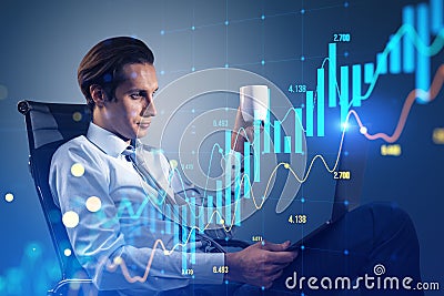 Attractive young businessman sitting and using laptop glowing candlestick forex chart on blurry blue background. Trade, finance Stock Photo