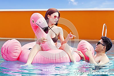 Attractive couple with inflatable flamingo at pool Stock Photo
