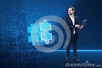 Attractive young european businessman using laptop with abstract glowing jigsaw puzzle on blue background. Digital solution, Stock Photo