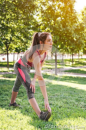 attractive young female athlete stretching calves on a green park Stock Photo