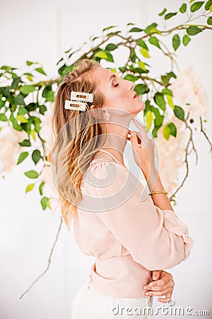 Attractive young girl with blond curly hair and beautiful make-up in a chiffon blouse with white orchids Stock Photo