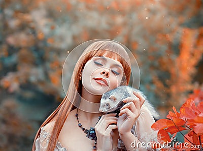 Attractive young girl with fiery red straight hair plays with her pet, elf princess plays animal fairy with wild ferret Stock Photo