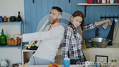 Young joyful couple have fun dancing and singing while set the table for breakfast in the kitchen at home Stock Photo