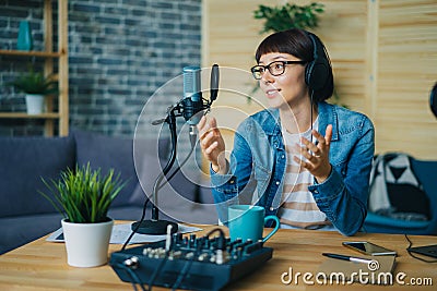 Attractive young lady speaking in microphone gesturing in studio Stock Photo