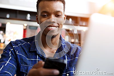 Attractive young man with cellphone and laptop in cafe Stock Photo