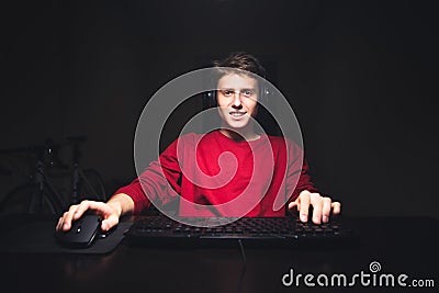 Attractive young man enjoys a computer at home at night, looks at the camera and smiles Stock Photo