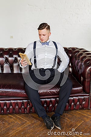 Attractive young man, future generation businessman seat on sofa and looking on portrait Stock Photo
