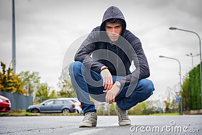Attractive young man with hoodie and baseball cap in city street Stock Photo
