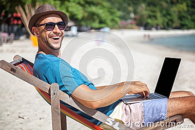 Attractive young man with laptop working on the beach. Freedom, Stock Photo