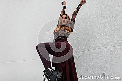 Attractive young red-haired woman in a vintage patterned blouse in an elegant purple cape in stylish pants posing Stock Photo