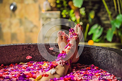 Attractive Young woman in bath with petals of tropical flowers and aroma oils. Spa treatments for skin rejuvenation Stock Photo