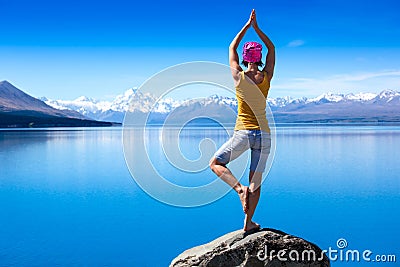 An attractive young woman doing a yoga pose for balance and stretching near the lake Stock Photo