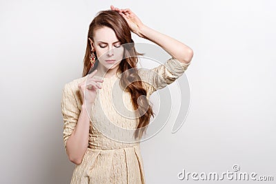 Attractive young woman in golden dress is standing, raising his hands to his face Stock Photo