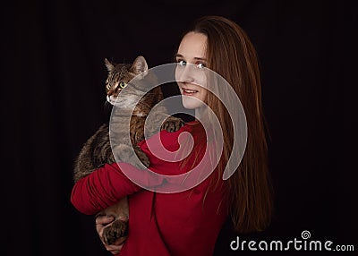 Attractive young woman with long hair with huge brown marble tabby male cat with green-yellow eyes in her arms Stock Photo