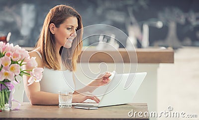 Attractive young woman online shopping using computer and credit card in home kitchen Stock Photo