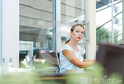 Attractive young woman reads a newspaper sitting in a cafe Stock Photo