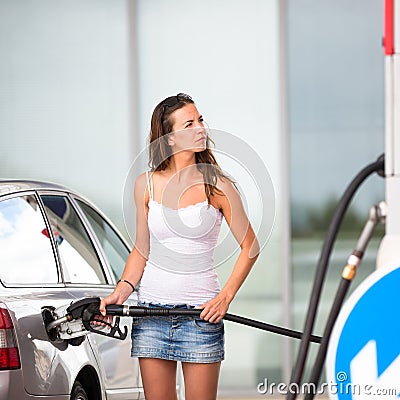 Attractive, young woman refueling her car in a gas station Stock Photo